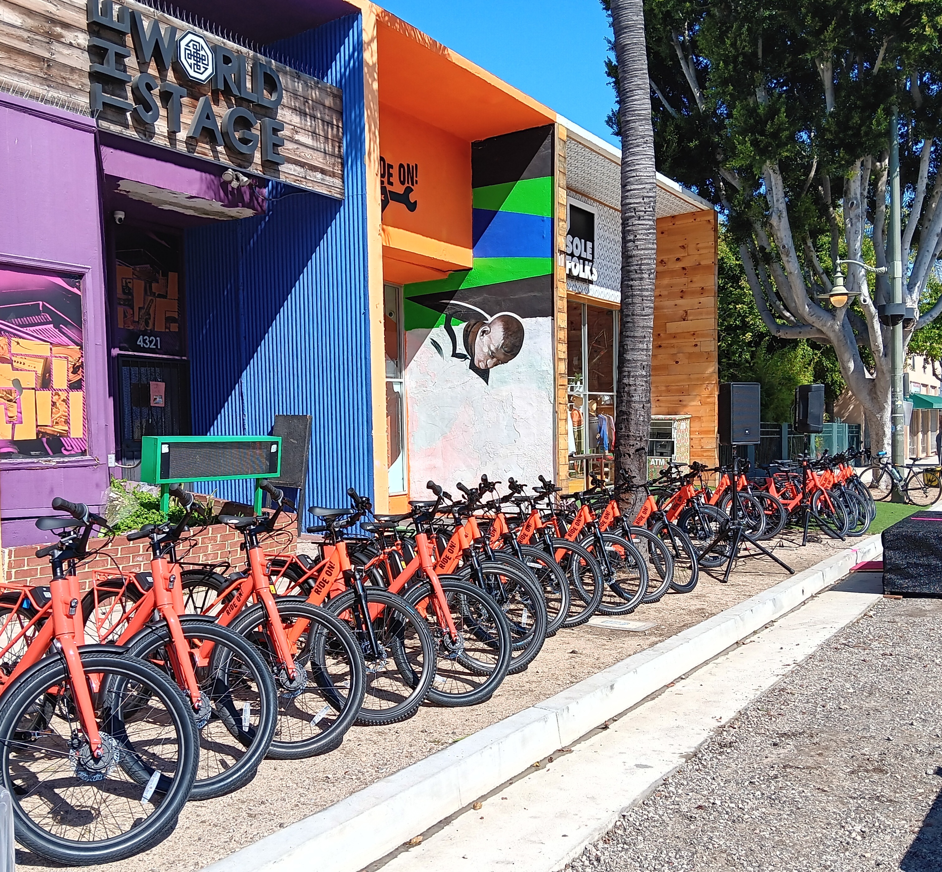 row of orange ebikes in front of colorful store front